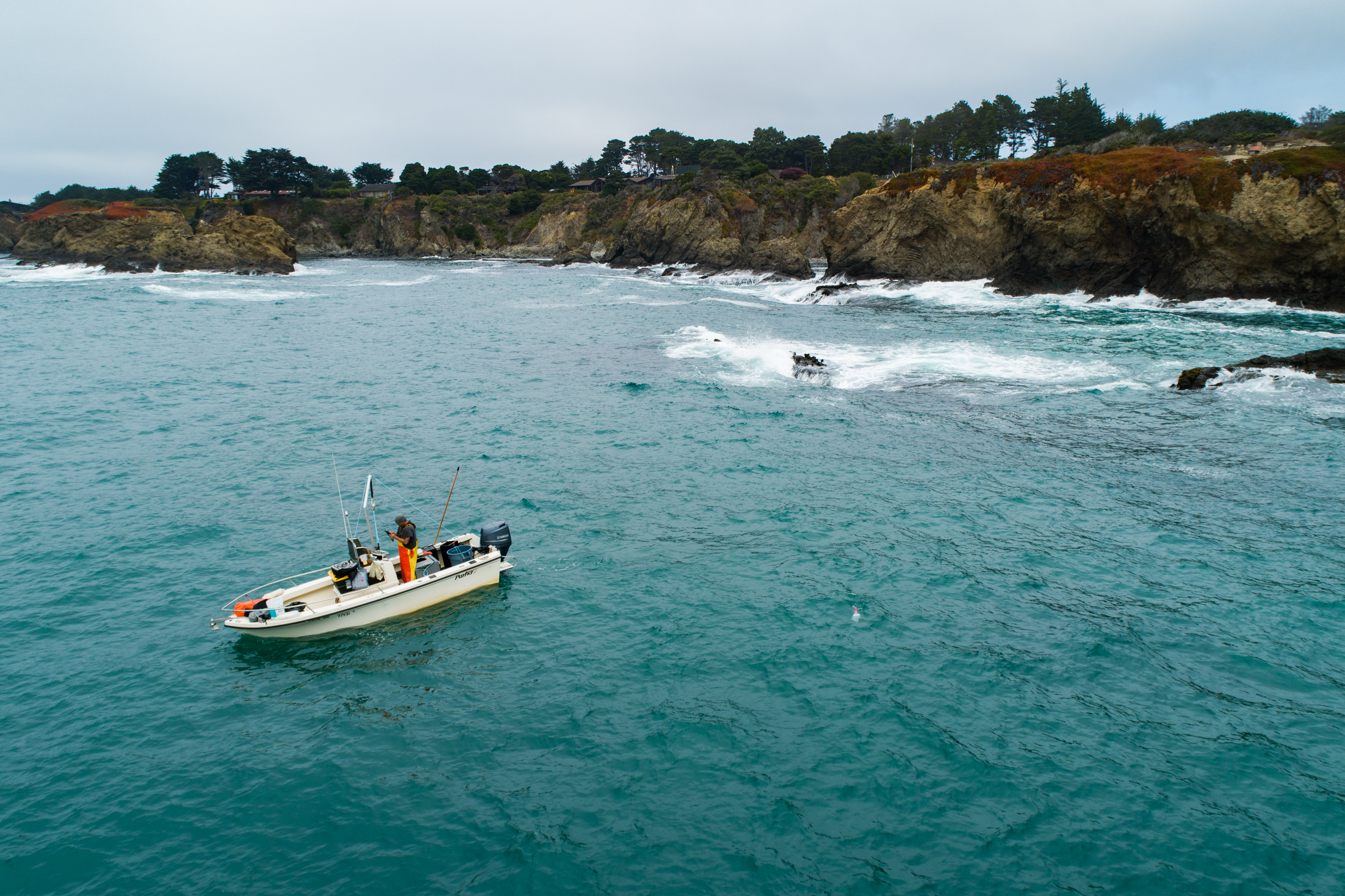A boat in the water next to a rocky coastline.